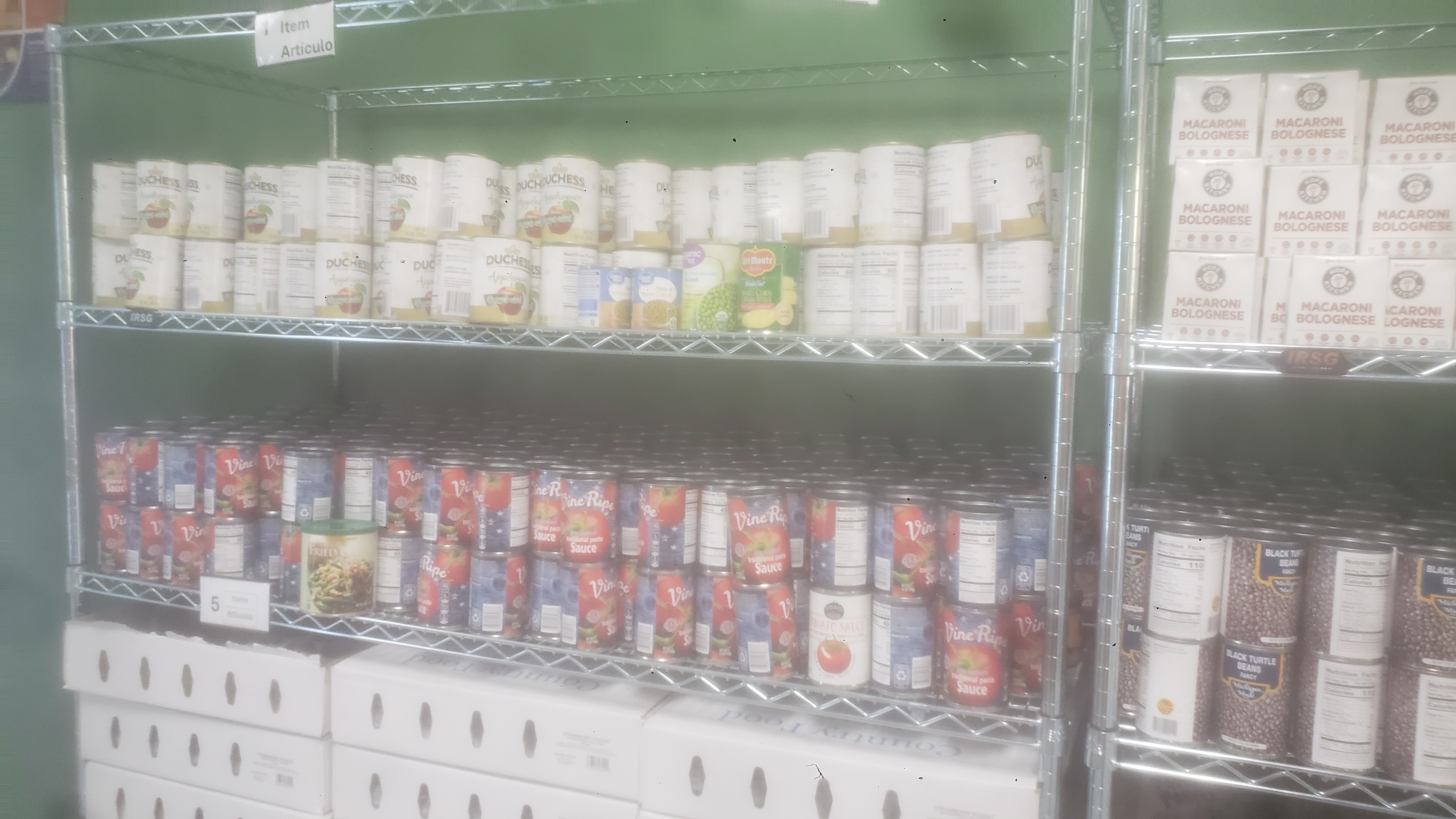 Cans of applesauce, cans of tomato sauce, packets of dried cranberries, boxes of yogurt, and miscellaneous items on a shelf.